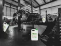 Warsztat samochodowy, Jeep na podnośniku, mechanik pracuje. Na pierwszym planie kanistry z napisem "benzyna ekstrakcyjna".