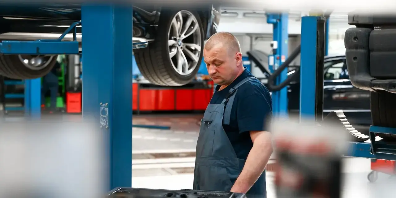 Mechanik w warsztacie, samochód na podnośniku. Sprawdza sprzęt do dynamiczna wymiana oleju dsg cena.