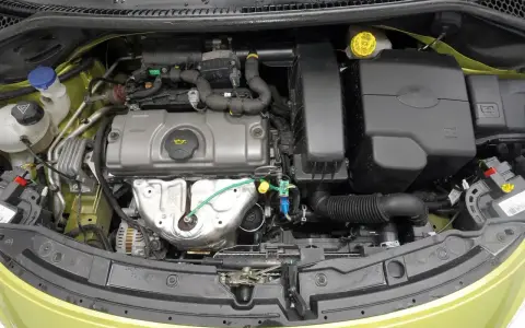 Silnik Peugeot 207, widok z góry. Widać elementy układu dolotowego, pokrywę zaworów i alternator.