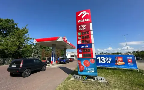 Stacja paliw Orlen z cennikiem paliw: benzyna 95 za 6.48 zł, diesel za 6.89 zł, LPG za 3.75 zł. Obok reklama hot doga i napoju.