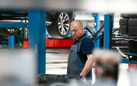 Mechanik w warsztacie, samochód na podnośniku. Sprawdza sprzęt do dynamiczna wymiana oleju dsg cena.