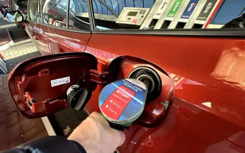Tankowanie czerwonego auta na stacji Orlen. Dystrybutor z etykietą Vitay, promującą punkty i zniżki, jak na karcie dużej rodziny Orlen.