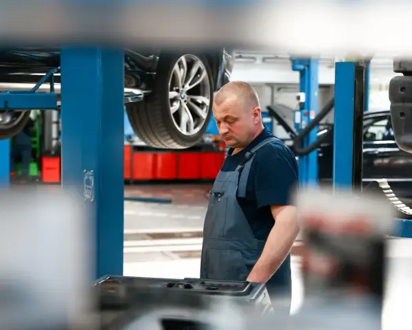 Mechanik w warsztacie, samochód na podnośniku. Sprawdza sprzęt do dynamiczna wymiana oleju dsg cena.