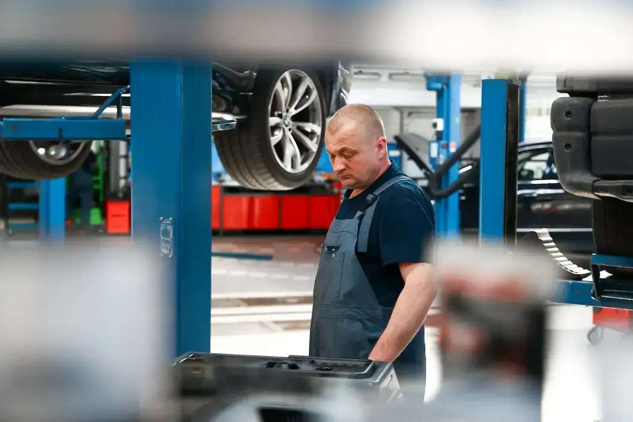 Mechanik w warsztacie samochodowym, przygotowuje się do dynamicznej wymiany oleju DSG. Cena usługi jest konkurencyjna.