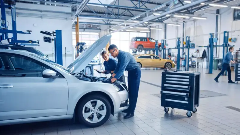 Mechanicy badają silnik srebrnego auta, szukając objawów uszkodzonego sterownika LPG.